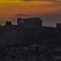 the sun is setting over the parthenon in greece