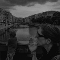 a woman smoking a cigarette on a bridge over a river